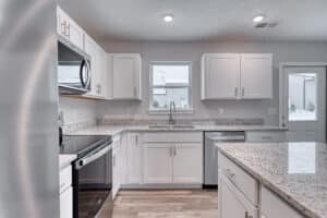 Modern white kitchen featuring granite countertops and stainless steel appliances for stylish cooking.