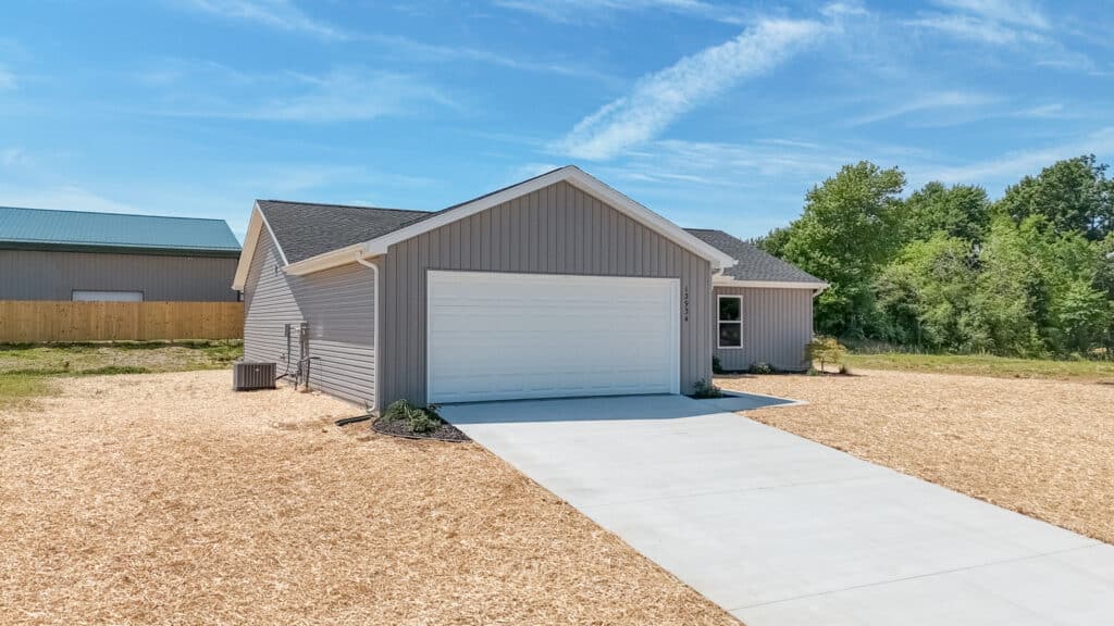 Modern gray home exterior with a spacious driveway and clear blue sky.