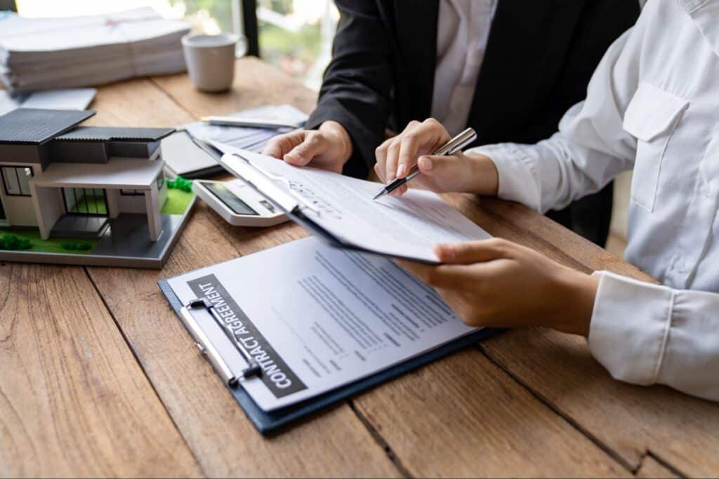 Business professionals signing a contract with a model house on the table.