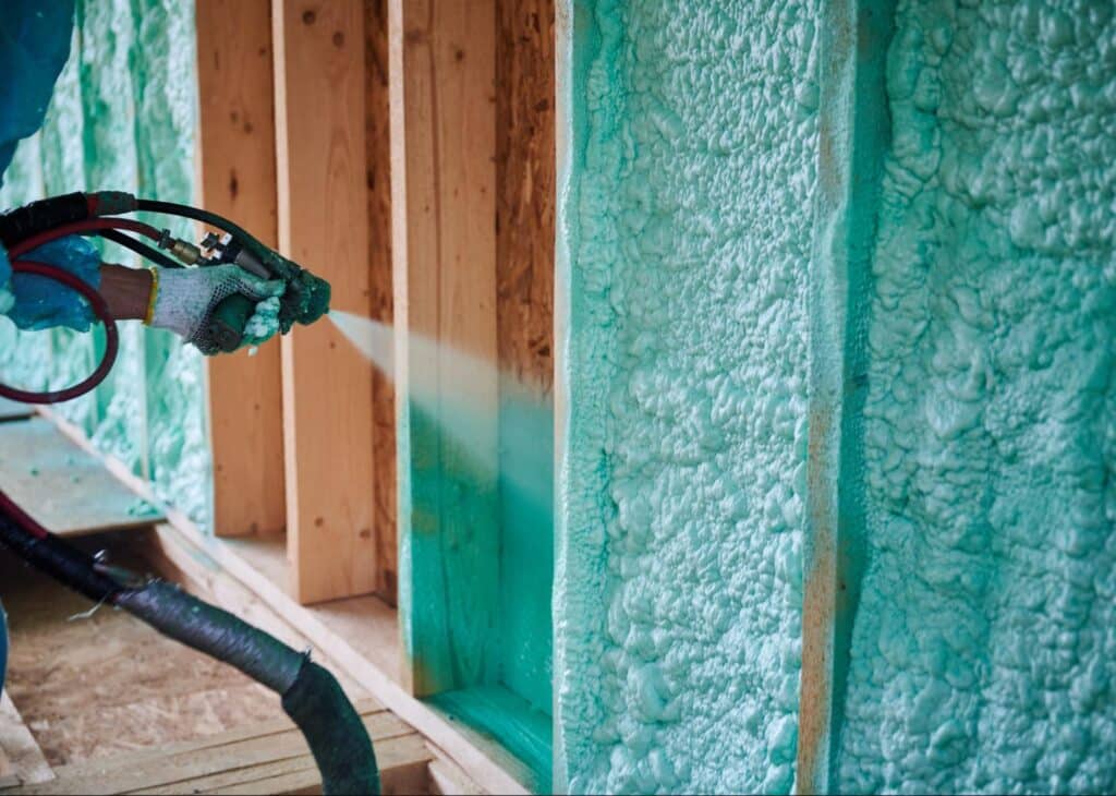 Applying spray foam insulation for improved energy efficiency in home building.
