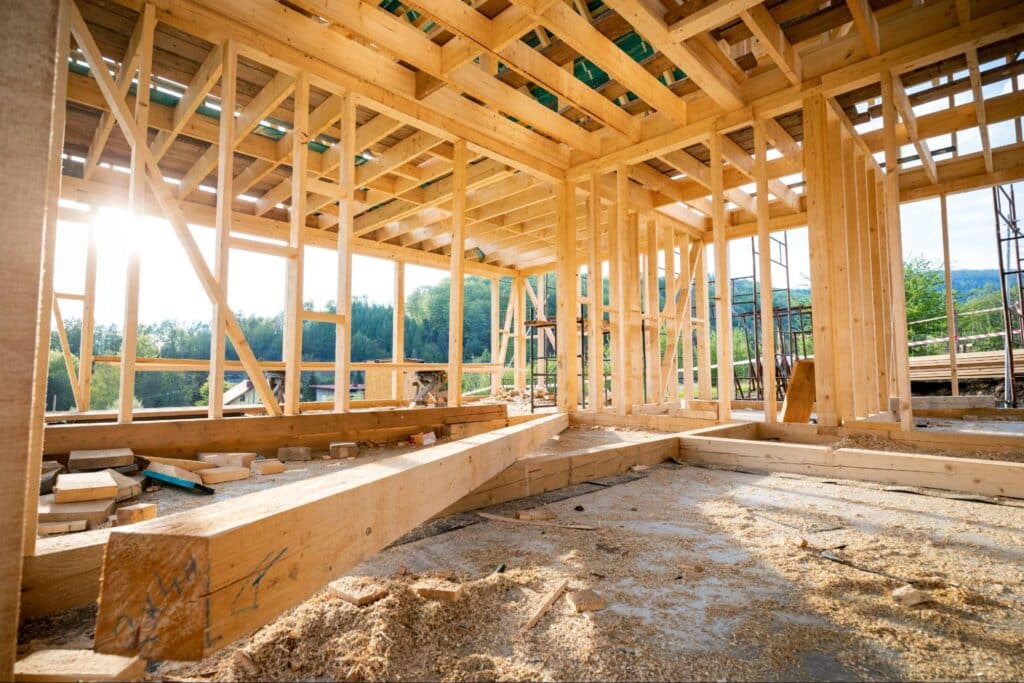 Wooden frame structure illuminated by natural light on a construction site.
