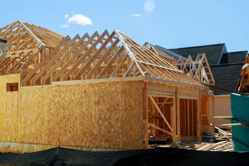 Newly framed home construction beneath a sunny, clear blue sky.
