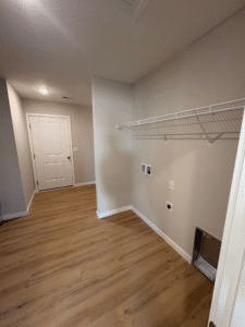 Modern laundry room with organized shelves and stylish wood flooring for optimal functionality.