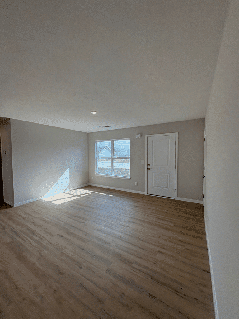 Spacious waterfront living room with abundant natural light and hardwood floors.