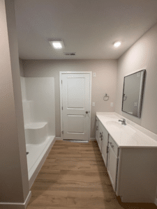 Minimalist bathroom featuring sleek design, modern fixtures, and warm wood-like flooring.
