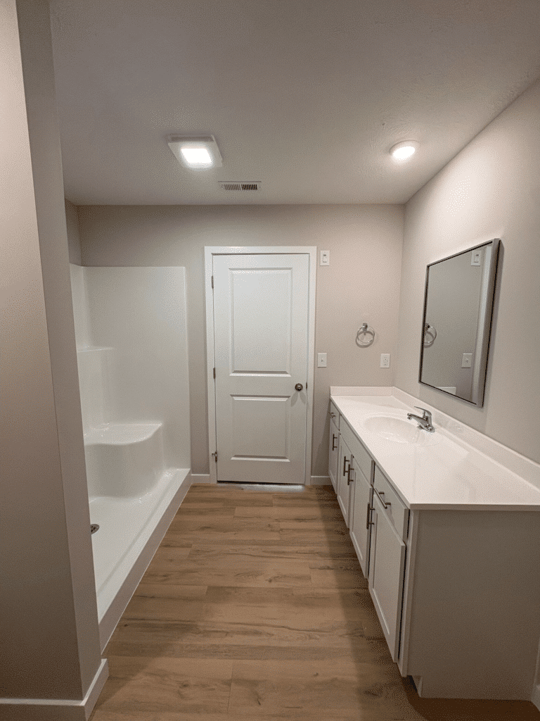 Minimalist bathroom featuring sleek design, modern fixtures, and warm wood-like flooring.