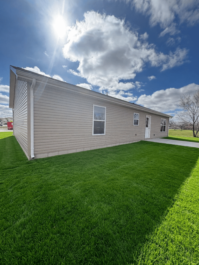Modern home exterior with a vibrant lawn under bright, scenic skies.