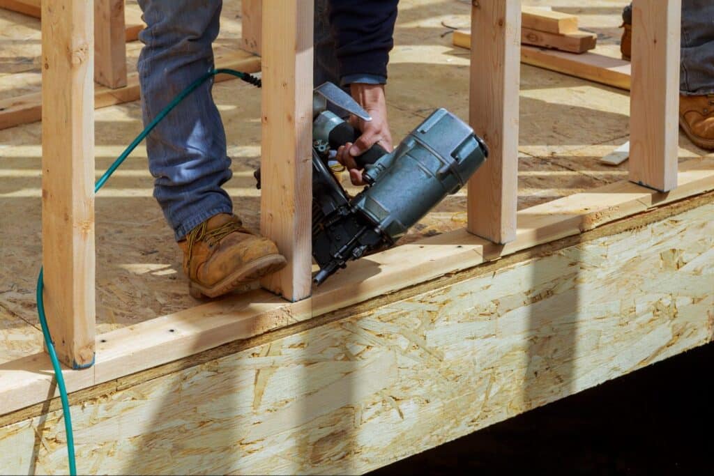 Carpenter using a nail gun to build a sturdy wooden frame.