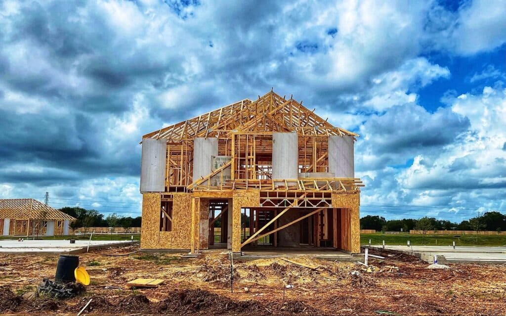 Framed house under construction with dramatic clouds looming above.