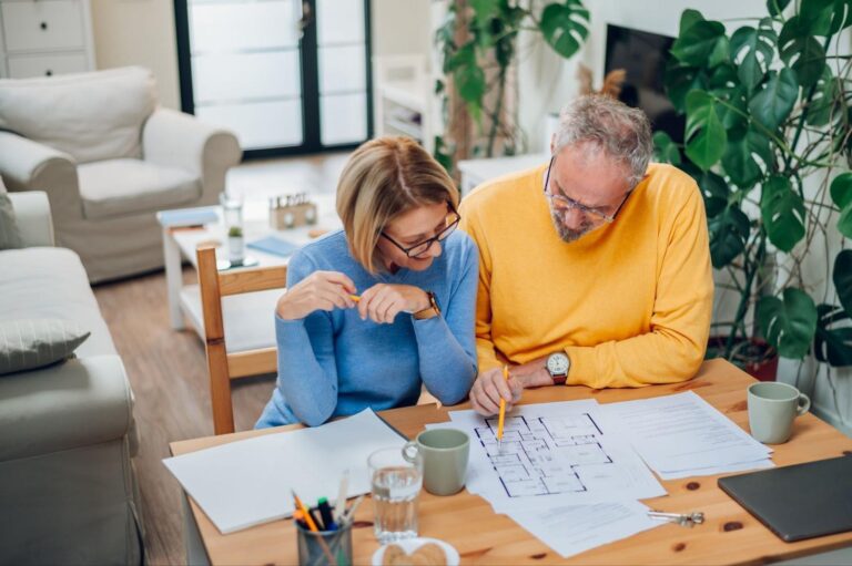 Couple reviewing home project plans together, surrounded by coffee and greenery.