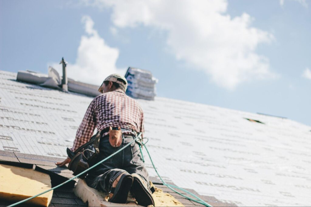 Roofer working on new shingle installation on a sunny day.