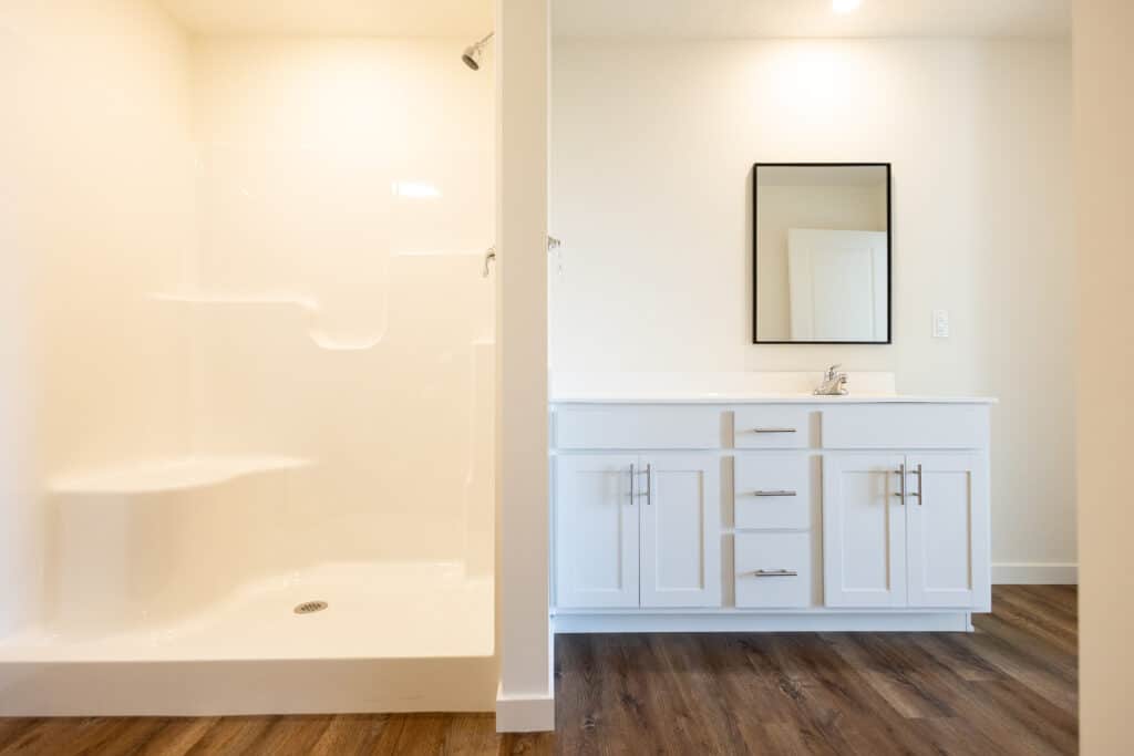 Modern bathroom interior featuring a spacious shower and sleek vanity with mirror.