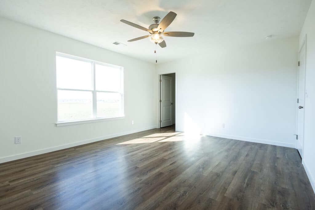 Bright, spacious room interior with large windows and modern ceiling fan for comfort.