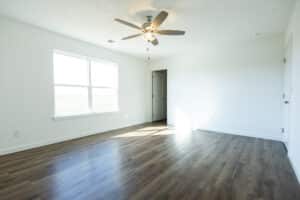 Bright, spacious room interior with large windows and modern ceiling fan for comfort.