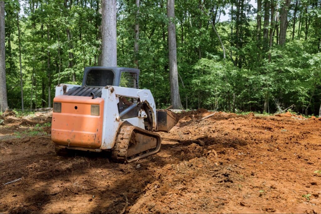 Bulldozer working in a wooded area to clear land for construction projects.