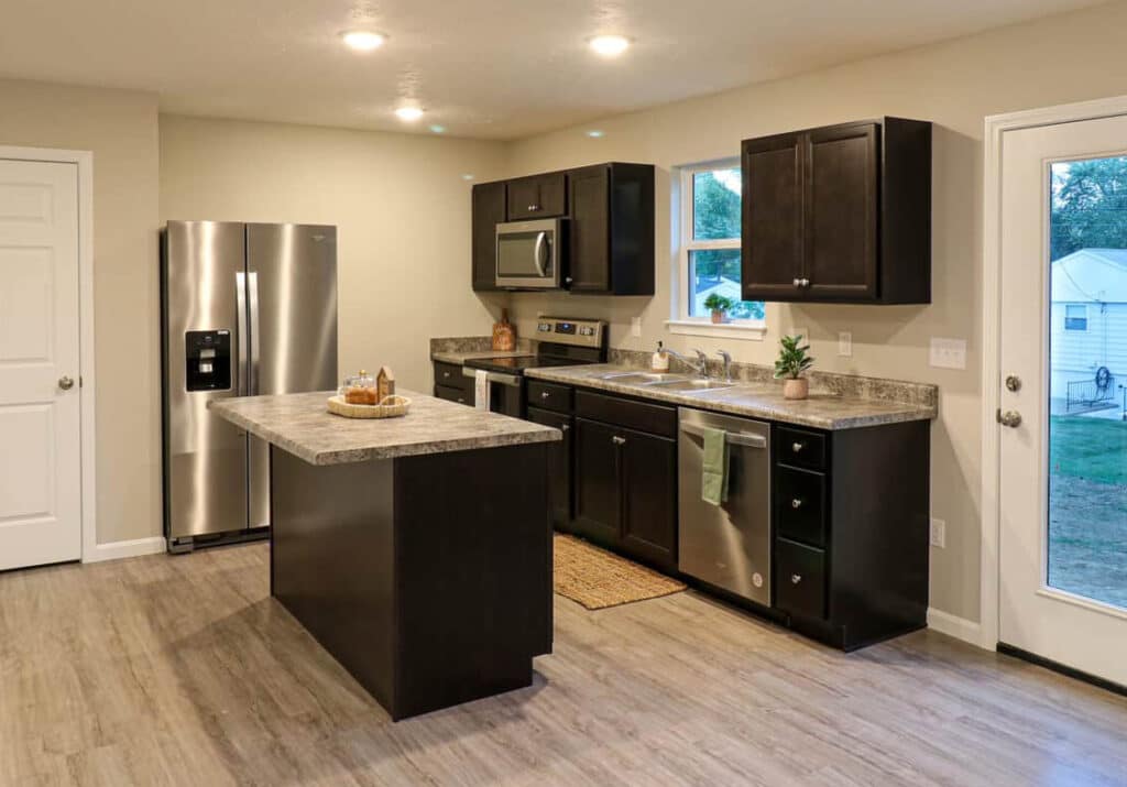 Stylish modern kitchen with dark cabinets, stainless appliances, and a functional island.