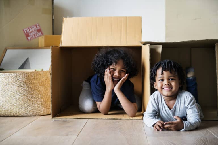 Kids joyfully playing in cardboard boxes during a house move.