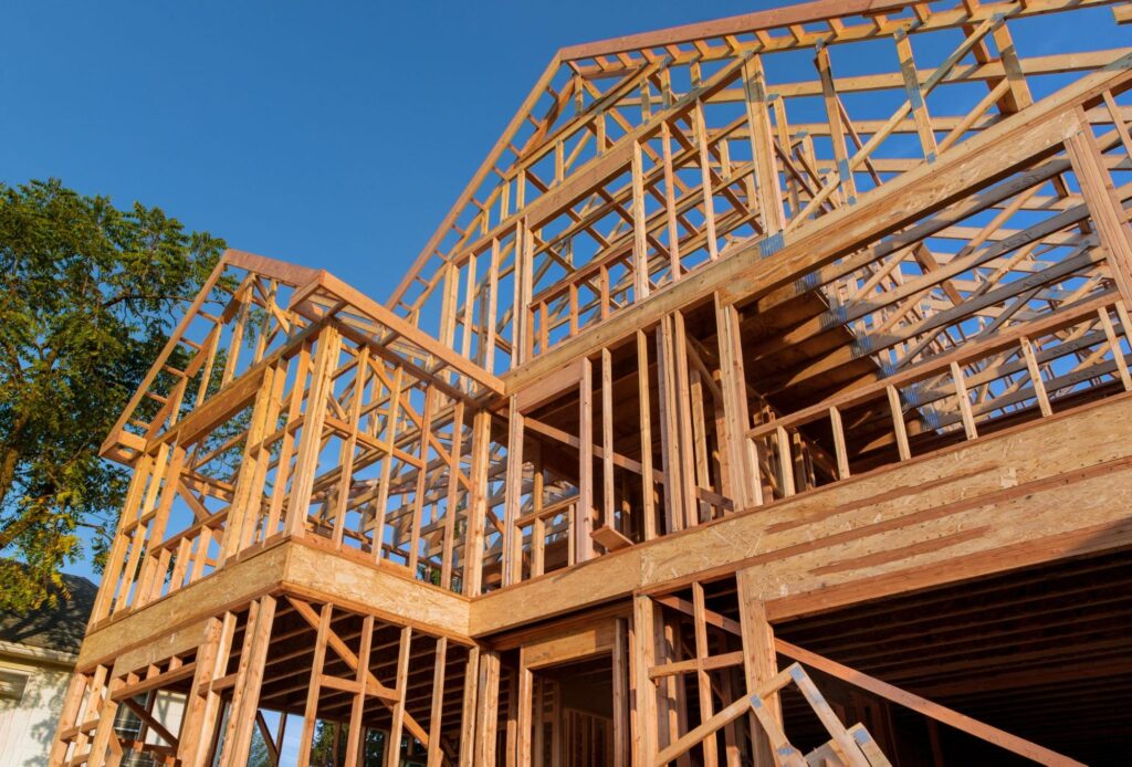 House framing under a beautiful sunrise, showcasing wooden construction techniques.