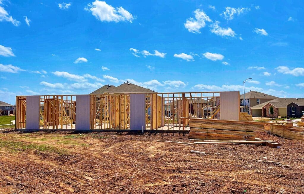New home construction with wooden frames and a clear blue sky backdrop.