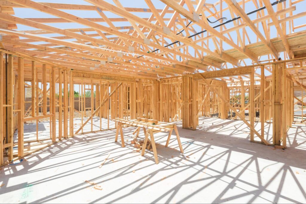 Framing worksite with wooden structures and sunlight creating unique shadow patterns.