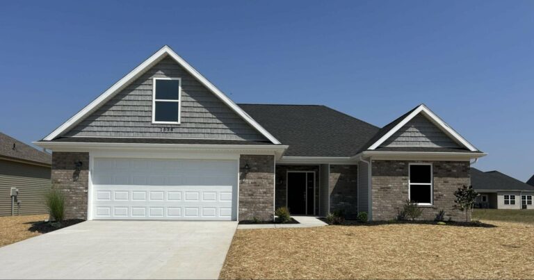 Stylish new home with a modern design and fresh landscaping on a clear day.