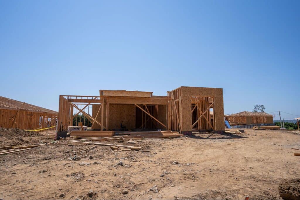 New home construction in progress with framed structures and clear blue skies.