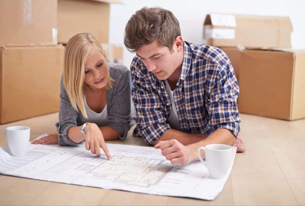 Couple planning home layouts while reviewing blueprints and discussing ideas.
